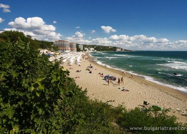 A crowded beach with colorful umbrellas and people enjoying the sun and sea on a sunny day.