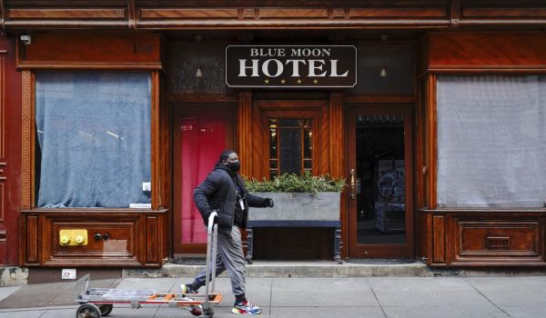 A man walking in front of the Blue Moon Hotel in Manhattan