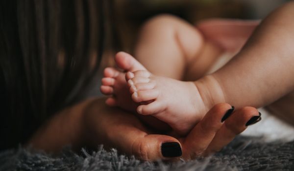 A Black woman holds her baby.