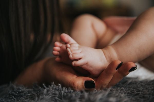 A Black woman holds her baby.