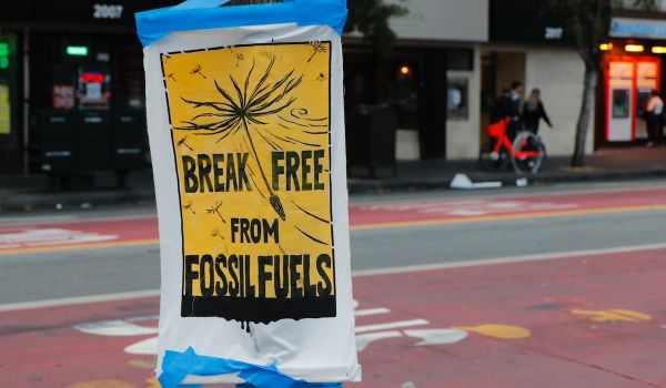 A black and yellow sign taped to a pole that reads, 'Break Free from Fossil Fuels'