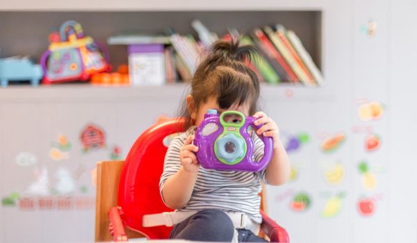 Child looks through lens on toy camera