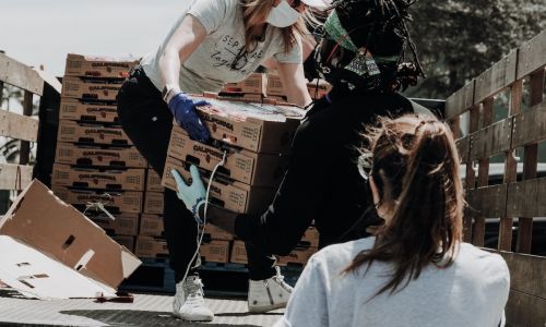 People unload boxes of produce from a pickup truck