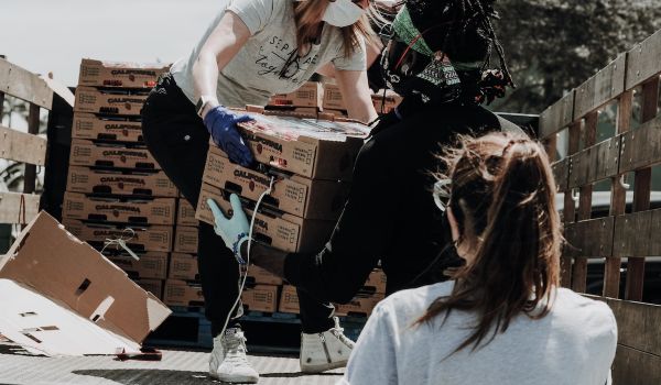 People unload boxes of produce from a pickup truck