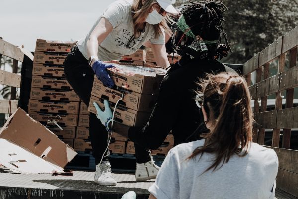 People unload boxes of produce from a pickup truck