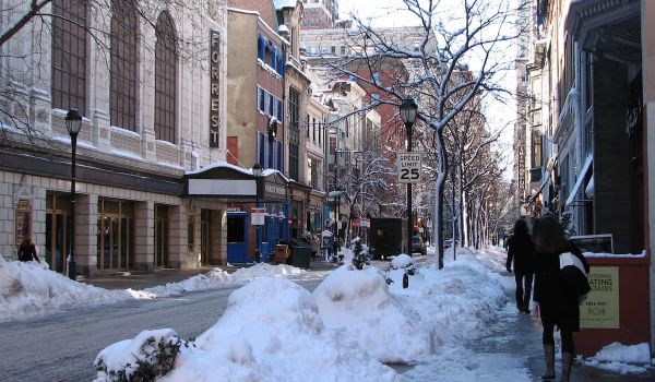 People walk on the sidewalk across from Forrest Theatre; there snow on the road and sidewalk