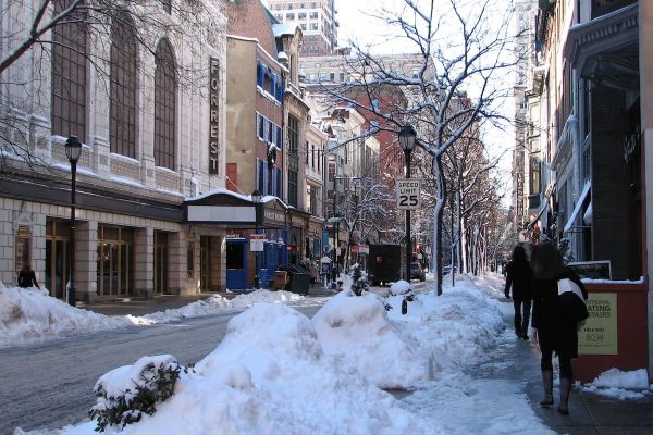 People walk on the sidewalk across from Forrest Theatre; there snow on the road and sidewalk