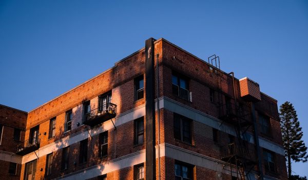 Brick apartment, blue sky in background and shadows on building