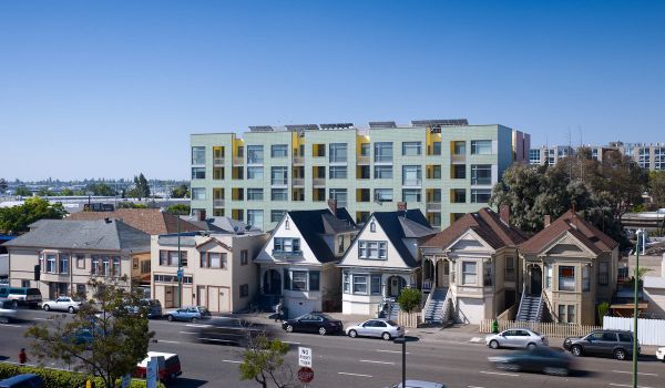 Street in Oakland where houses can be seen, with an apartment building behind them