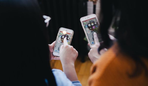 Two people hold mobile phones; view from behind