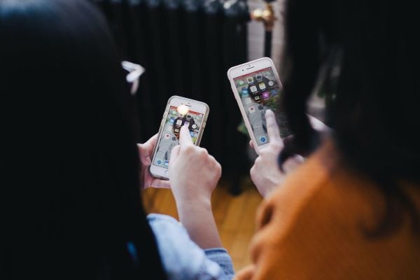 Two people hold mobile phones; view from behind