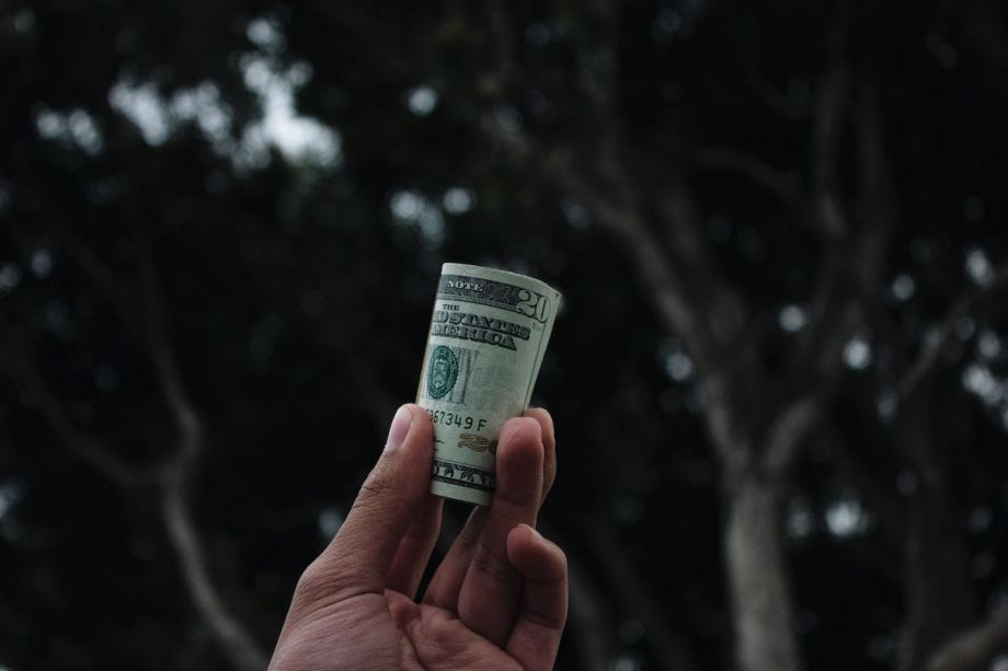 Person holds a roll of $20 bills