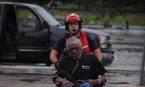 A pararescueman assigned to the New York Air National Guard pushes an elderly man toward the HH-60 Pave Hawk helicopter in Houston area, August 30, 2017.