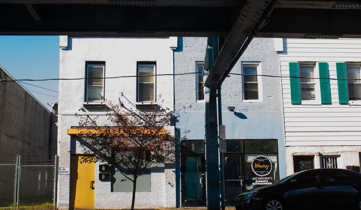 Image of two row home buildings beneath an elevates train platform.