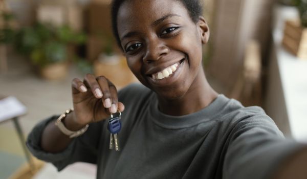 black woman holds up house keys