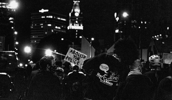 Police abolition protest at sign; a person holds a sign that reads, 'Abolish the police'