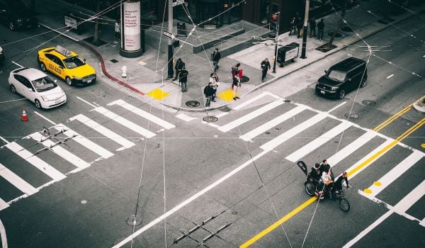 Intersection in San Fransisco where there are cars, a crosswalk, pedestrians and bikers