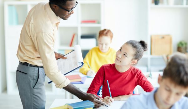 A teacher helps a student in the classroom.