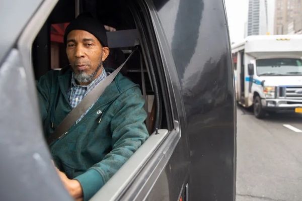 Winston Williams sitting in his car, he's wearing a green jacket