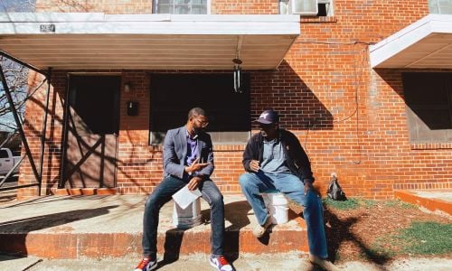 Mayor Woofin sits outside of a building with a resident of Birmingham